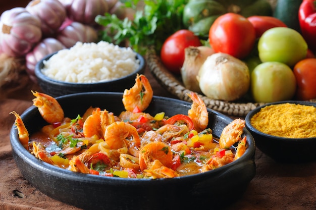 Camarão cozido em tigela de barro com arroz e farinha de mandioca. Culinária brasileira.