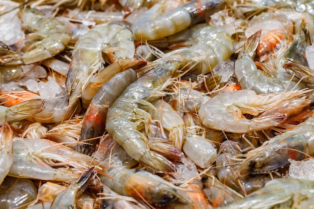 Camarão cru a granel no gelo no foco seletivo do mercado de peixe