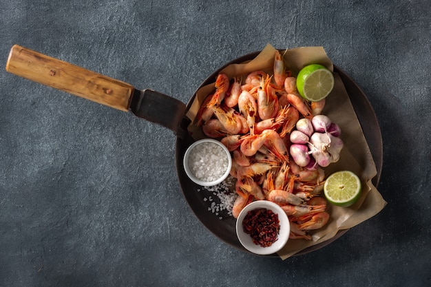 Camarão cru em uma panela com ingredientes para a preparação de camarão frito em uma vista superior escura