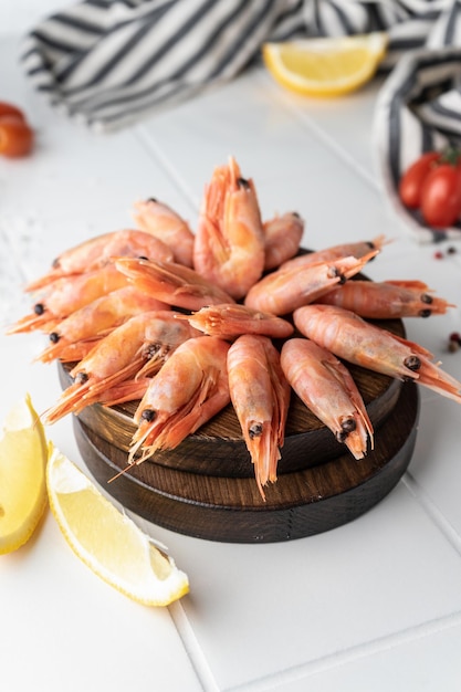 Foto camarão descascado descongelado, frutos do mar, iguaria. em um fundo branco, em um prato. bela apresentação do produto