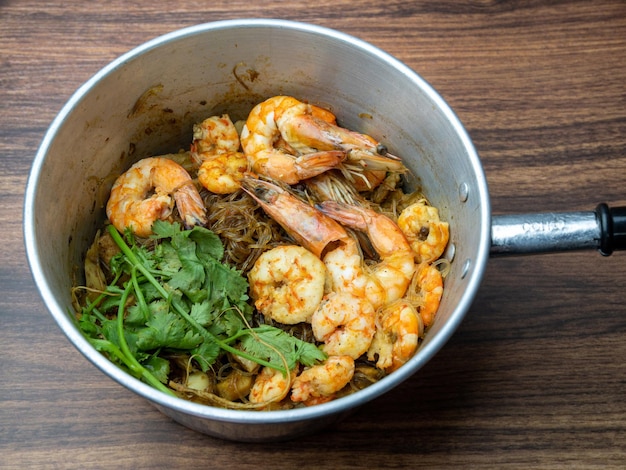 Camarão em vaso com aletria ou macarrão de vidro na mesa de madeira