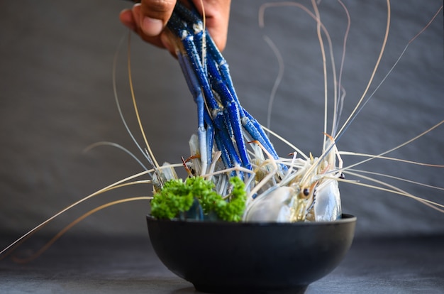 Camarão fresco de camarão com salsa verde limão de especiarias para cozinhar comida tailandesa de tom yum kung em fundo escuro no restaurante de frutos do mar - camarão cru na tigela