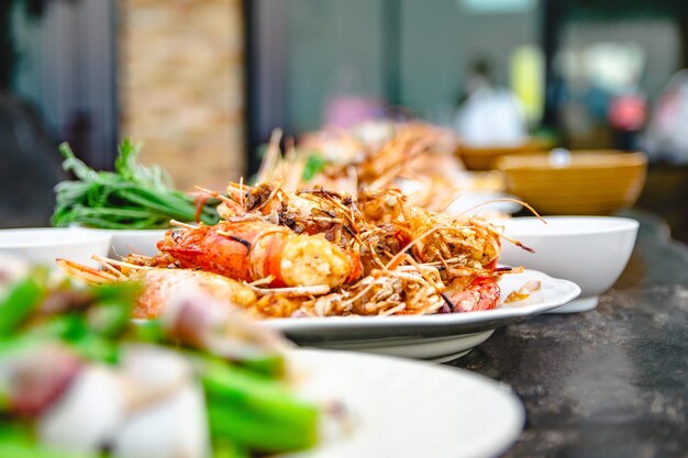 Foto camarão frito, alho, frutos do mar do restaurante com outros pratos ao fundo