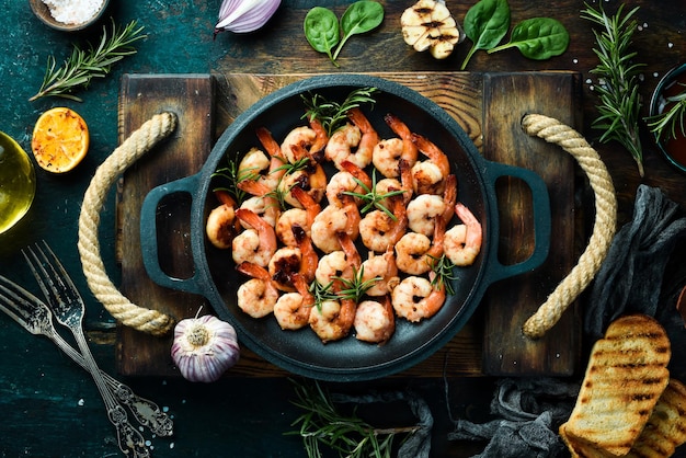 Camarão frito com alho e limão em uma panela frutos do mar em um fundo de pedra preta