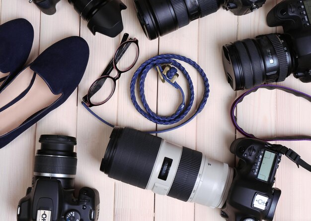 Foto cámaras modernas con cinturón de zapatos femeninos y gafas en la vista superior de la mesa de madera