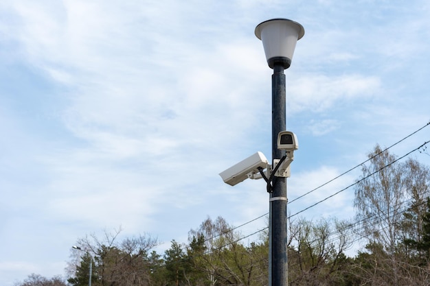 Cámaras de vigilancia montadas en un poste de luz al lado de una cámara cctv de seguridad de camino forestal Seguridad en la ciudad Filmación oculta de lo que está sucediendo Tecnologías y equipos modernos