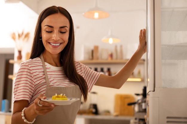 Foto camarera de cafetería sosteniendo plato con pastelito