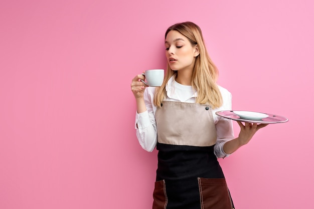Camarera disfrutando de café caliente aislado sobre fondo rosa studio