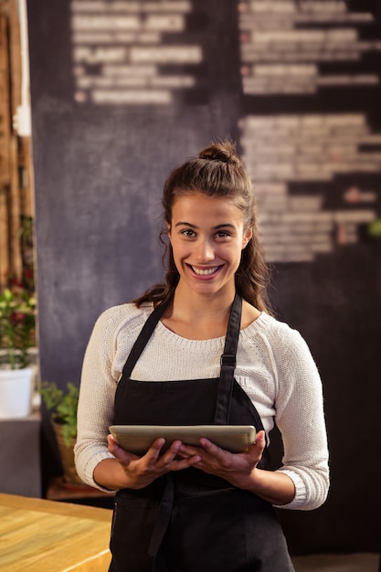 Camarera de pie con tableta digital en cafetería