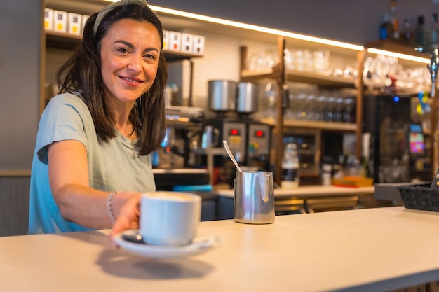 Camarera sonriente en la cafetería con el café preparado entregándoselo al cliente las restricciones debidas al covid