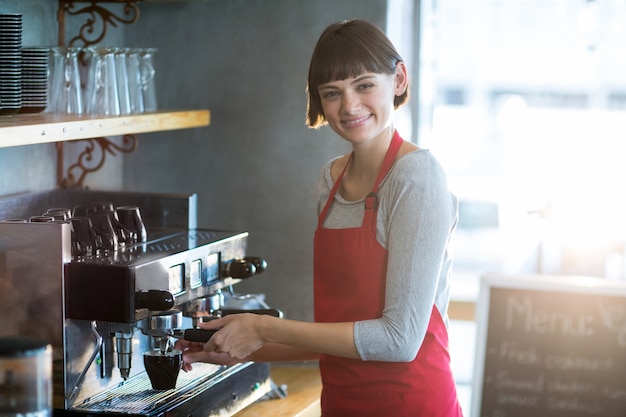 Camarera sonriente haciendo una taza de café en la cafetería