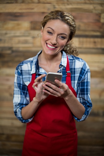 Camarera sonriente con teléfono móvil en café