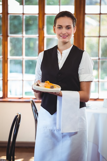 Camarera sosteniendo un plato con pasteles