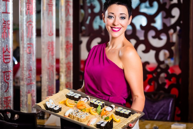 Camarera con sushi en restaurante asiático.
