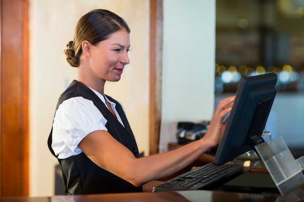 Foto camarera usando una computadora en el mostrador