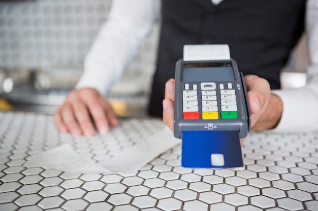 Camarero aceptando una tarjeta de crédito en la barra de bar