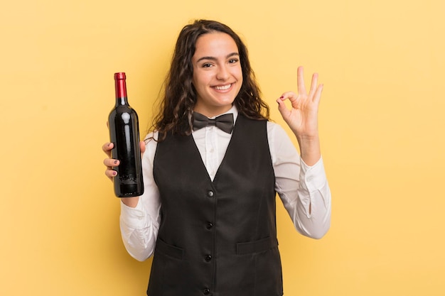 Camarero bastante joven de la mujer hispana con una botella de vino