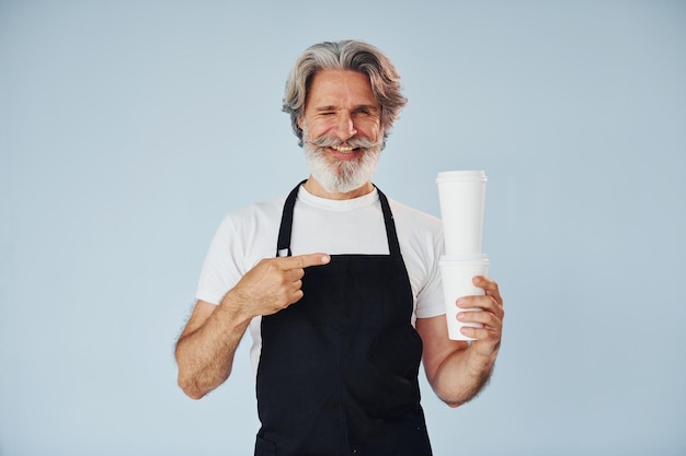 Camarero con bebidas en las manos Senior elegante hombre moderno con cabello gris y barba en el interior