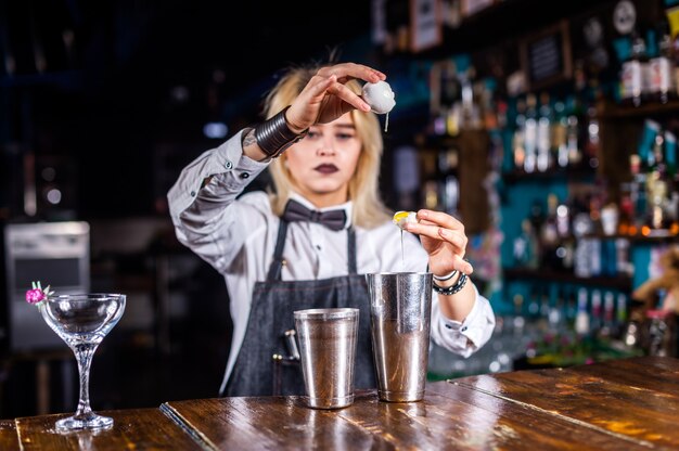 Camarero chica hace un cóctel en la cervecería