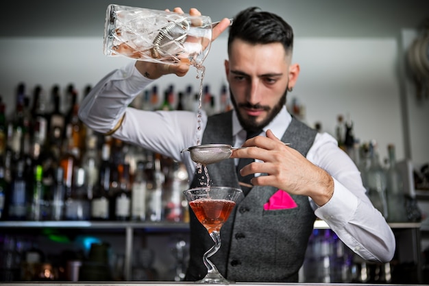 Camarero con colador vertiendo bebida en vaso