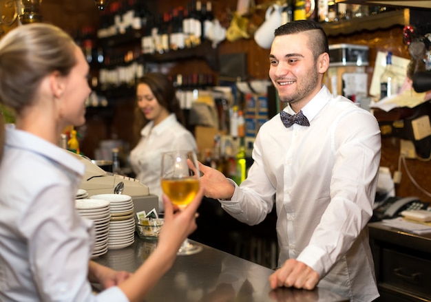 Camarero dando vino a la mujer