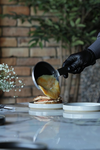 Camarero derramando un huevo frito en un sándwich de hamburguesa de la sartén al sándwich directamente