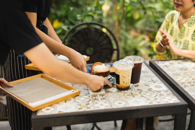 Camarero entrega bebida de café helado al cliente en café al aire libre