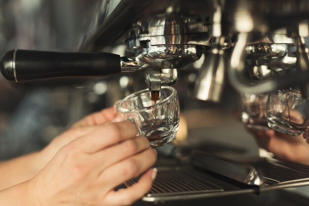 Camarero experimentado que hace espresso en una máquina de café moderna. Primer plano de una mano femenina preparando bebidas vigorizantes. Concepto de elaboración de café para pequeñas empresas y profesionales