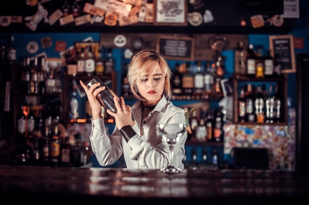 Camarero experto vertiendo bebida alcohólica fresca en los vasos en el bar de cócteles