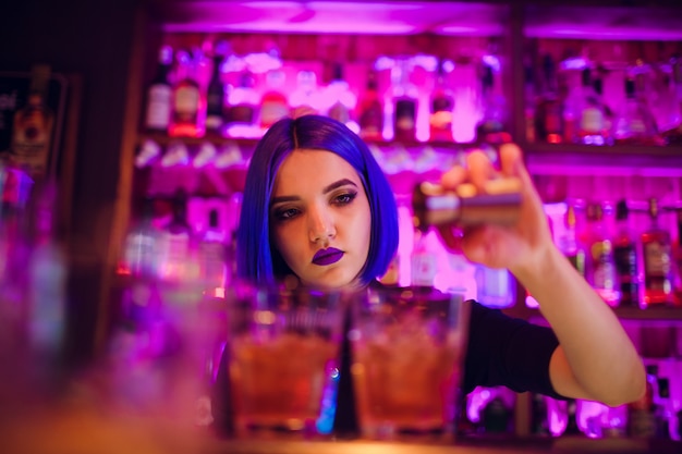 Camarero femenino. Chica con el pelo azul. coctelería en bar nocturno