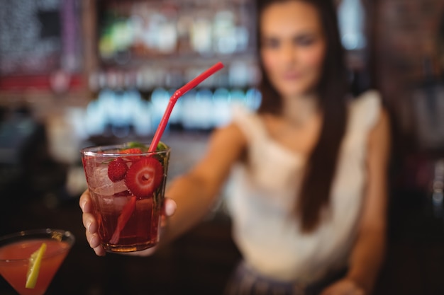 Camarero femenino sirviendo un cóctel en el mostrador de bar