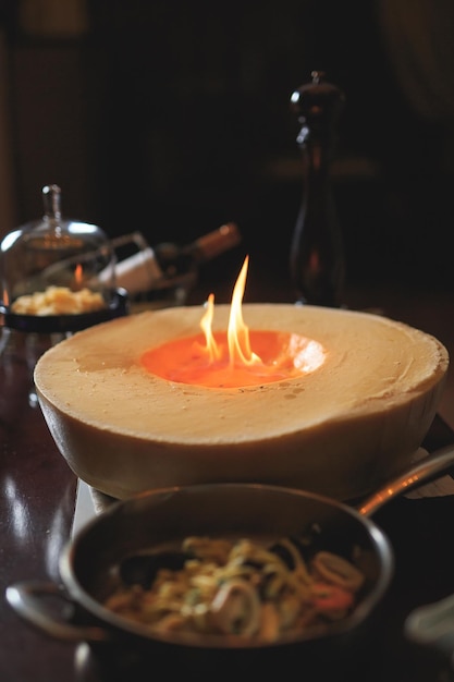 El camarero flambea queso parmesano en el restaurante para invitados