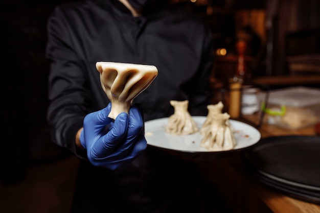 Un camarero con un guante sostiene un khinkali en la mano.