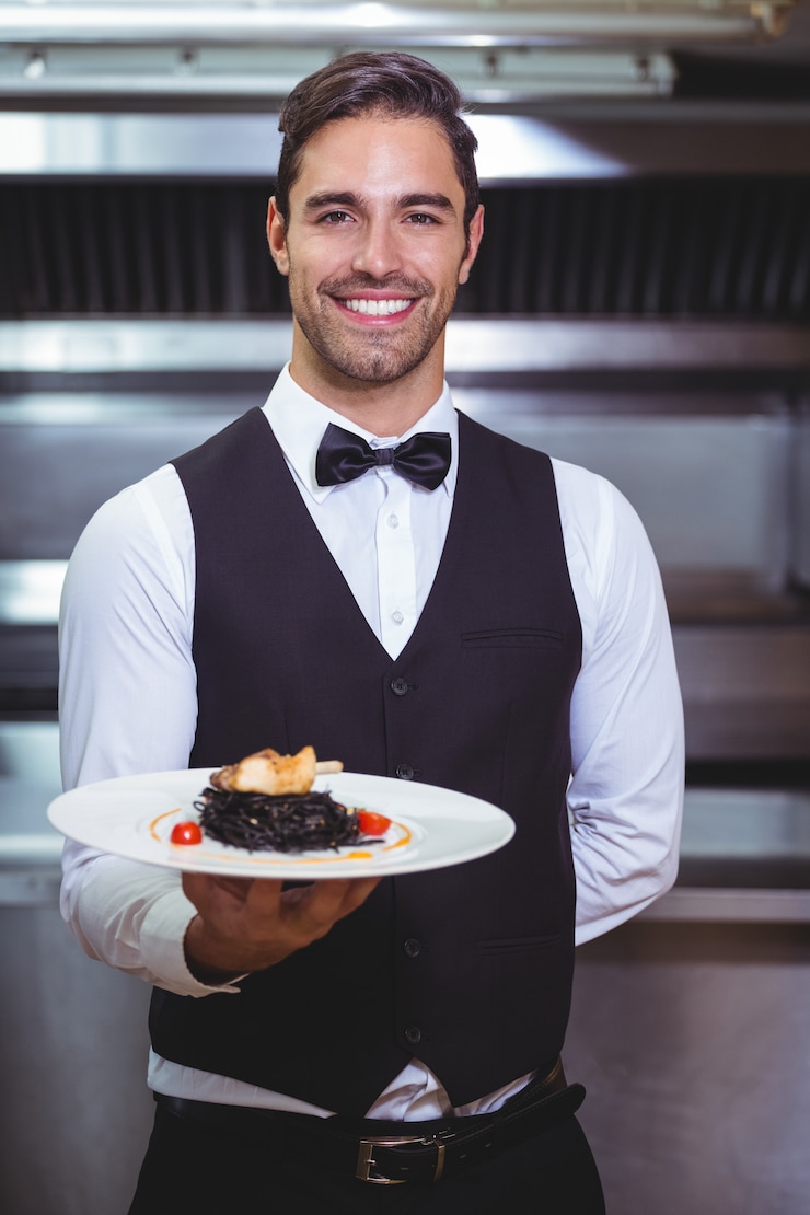 Foto camarero guapo sosteniendo un plato de espaguetis con tinta de calamar