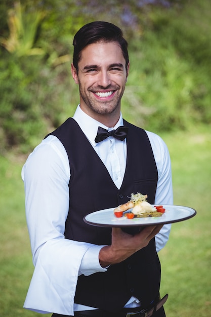 Camarero guapo sosteniendo un plato