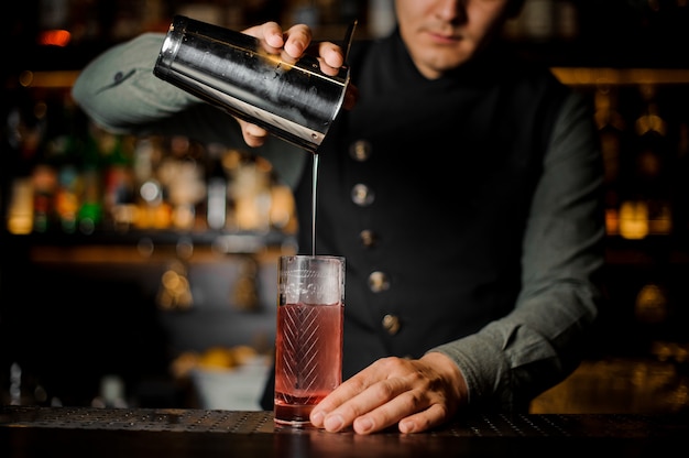 Camarero haciendo un cóctel agrio ligero de verano con licor de durazno rosa