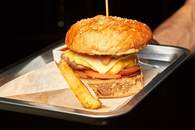 Foto camarero con hamburguesa con carne, queso y patatas rústicas