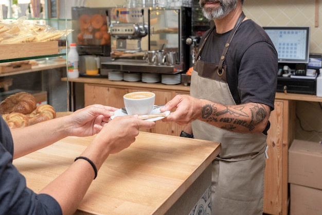 Camarero irreconocible sirviendo una taza de café al cliente en la cafetería