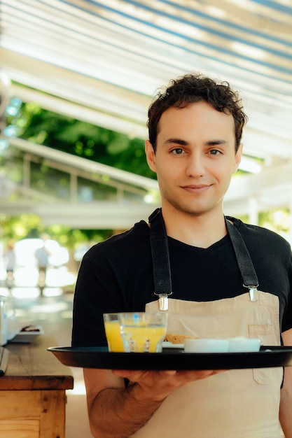 Foto camarero joven que sostiene la bandeja.