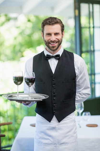 Foto camarero masculino con bandeja con copas de vino en el restaurante