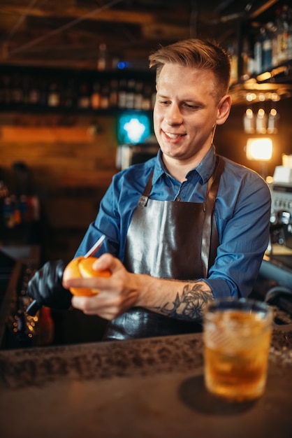 Camarero masculino limpia naranja en la barra del bar