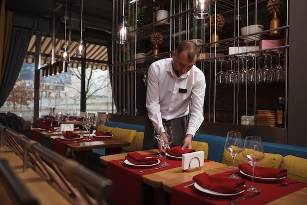 Camarero masculino preparando mesas antes de abrir el restaurante, espacio de copia