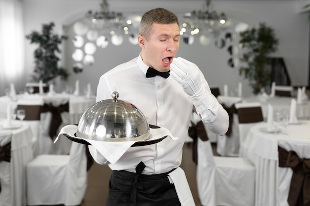 El camarero masculino en un restaurante con un plato en las manos muestra que este plato no tiene sabor