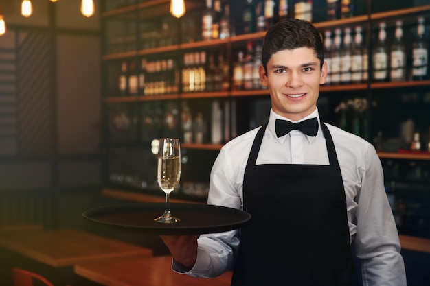 Foto camarero masculino sosteniendo una bandeja con champán en el café