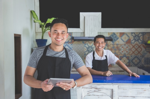 Camarero masculino con tableta digital en café