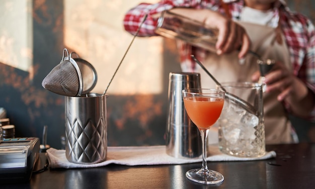 Camarero masculino vertiendo los ingredientes que faltan al preparar un cóctel de bebidas alcohólicas