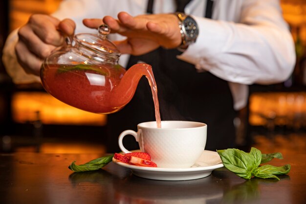 Camarero masculino vierte té caliente en el bar de un restaurante