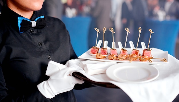 Foto camarero mujer con bandeja con canapé en servilleta blanca. foto de alta calidad