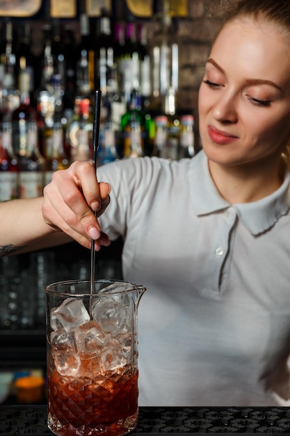 Camarero mujer haciendo un cóctel de alcohol en el bar.