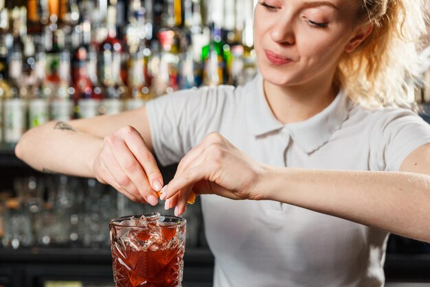 Camarero mujer haciendo un cóctel de alcohol en el bar.